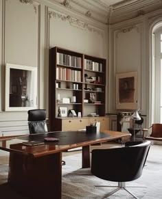 an office with two chairs and a desk in front of a large bookcase filled with books