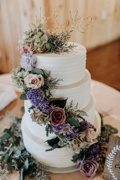 a white wedding cake with flowers and greenery