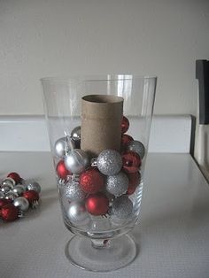 a glass vase filled with ornaments and a roll of paper sticking out of the top