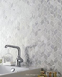 a white sink sitting under a faucet next to a wall mounted soap dispenser