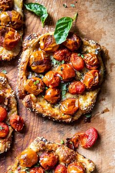 three pieces of bread with tomatoes and basil on top, sitting on a cutting board