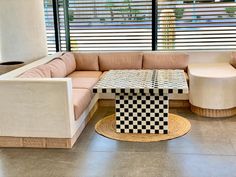 a living room with couches and tables in front of large windows that have blinds on them