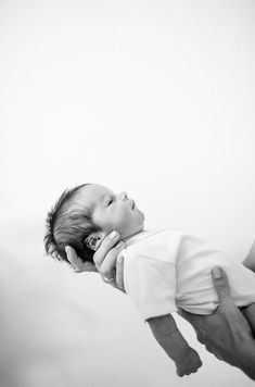 a woman holding a baby in her arms while she holds it up to the side