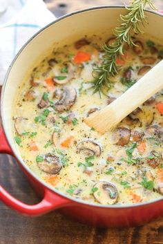 a red pot filled with mushroom soup on top of a wooden table