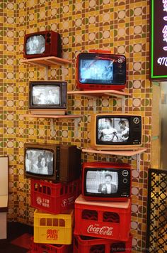 several televisions are stacked on top of each other in front of a wall with colorful tiles