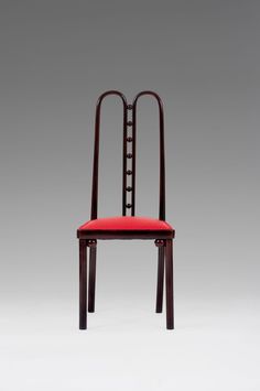 a red chair sitting on top of a white floor next to a gray wall in the background