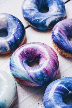 six doughnuts with different colors and designs on them sitting on a wooden table