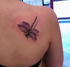 the back of a woman's shoulder with a dragonfly tattoo design on it