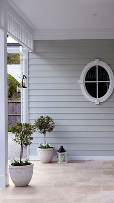 two potted plants sitting on the front porch next to a white door and window