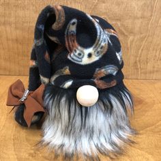 a black hat with white fur and a brown bow on the top is sitting on a wooden surface