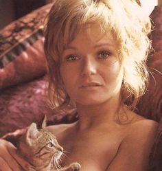 a nude woman holding a cat in her lap and looking at the camera with an intense look on her face