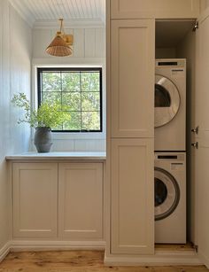 a washer and dryer are in the corner of this laundry room with white cabinets