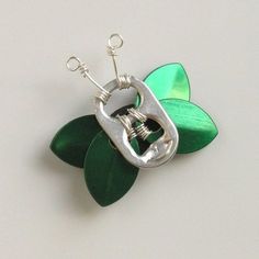 a brooch with a green leaf and metal clasp on the end, sitting on a white surface