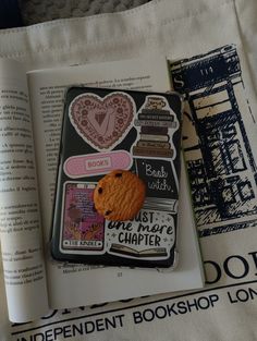 an open book with stickers on it and a cookie in the middle next to some books