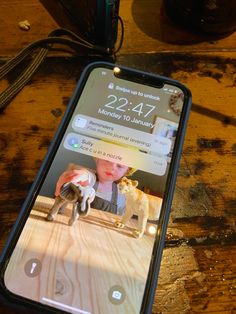 a cell phone with an image of a cat and dog on it sitting on a wooden table