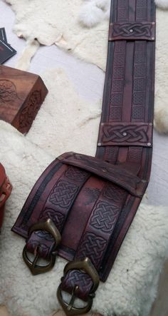 two leather belts are laying next to each other on a white surface with fur around them