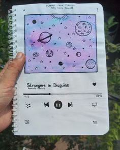 someone is holding up a notebook with drawings on the pages and an mp3 player in front of them