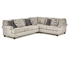 a large sectional couch with pillows on the top and bottom corner, in front of a white background