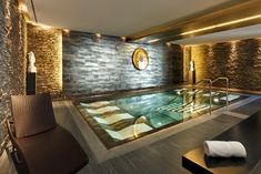 an indoor swimming pool with stone walls and flooring