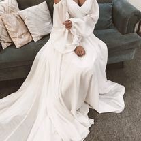 a woman sitting on top of a couch wearing a white dress