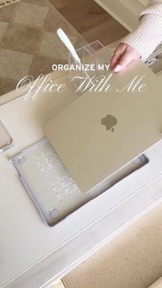 an apple laptop computer sitting on top of a white desk next to a person's hand