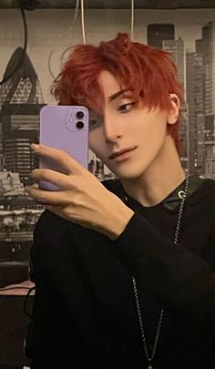 a man with red hair taking a selfie in front of a wallpapered cityscape