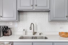 a kitchen with gray cabinets and white counter tops