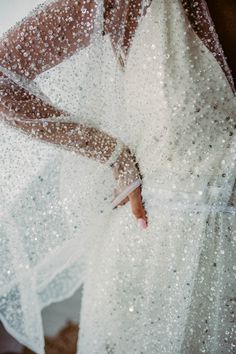 a woman in a white dress is holding her hand out to the side with water droplets on it