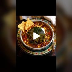 a bowl of chili and corn with tortilla chips