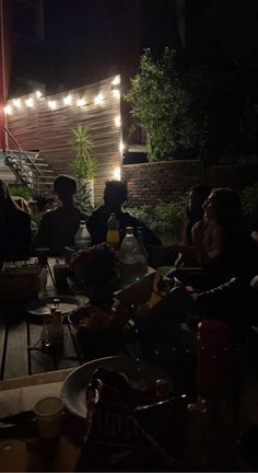 some people sitting at a table with food and drinks in front of an outdoor building