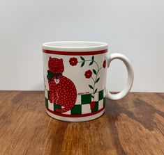 a red and green bear mug sitting on top of a wooden table