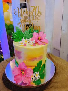 a colorful cake with flowers on it sitting on a table