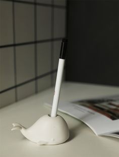 a pen sitting on top of a white table next to a magazine and some papers