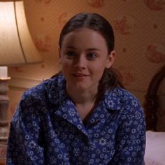 a woman sitting on top of a bed next to a lamp