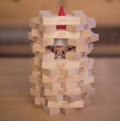 a small toy with a red hat on it's head peeking out from behind a white tower