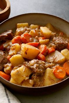 a bowl filled with meat and potatoes on top of a table