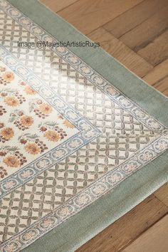 a close up of a rug on the floor with wood floors in front of it