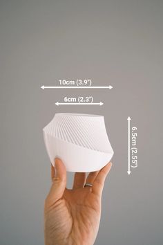 a hand holding up a white object with measurements for the top and bottom half of it