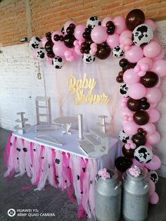 a cow themed baby shower with pink and black balloons, streamers, and decorations