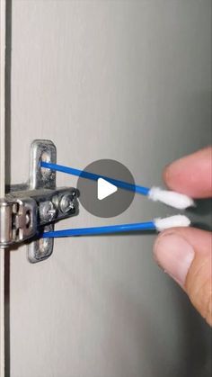 someone is holding two blue and white wires in their hand while they are opening the door