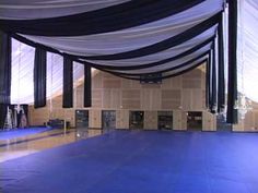 an empty dance floor with black and white draping on the sides, and blue carpet