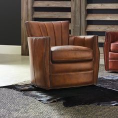 two brown leather chairs sitting on top of a rug