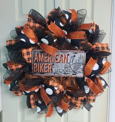 an orange and black mesh wreath with the american biker by choice on it is hanging on a door