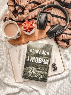 an open book, headphones and cup of coffee on a bed