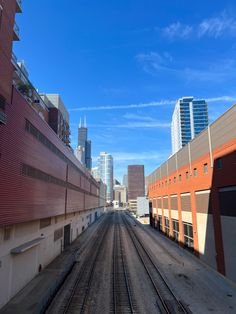 an empty train track in the middle of a city with tall buildings on either side