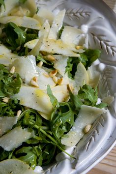 a salad with lettuce and pine nuts in a glass bowl