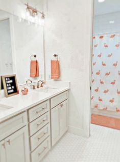 a white bathroom with orange towels hanging on the wall