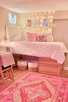 a bedroom with a pink rug and lights on the wall above it is decorated in pastel colors