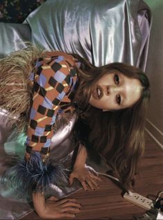 a woman laying on top of a wooden floor next to a metal sheet covered chair