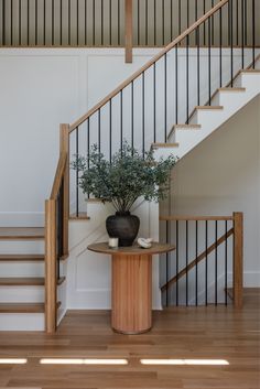 a potted plant sitting on top of a wooden table next to a stair case